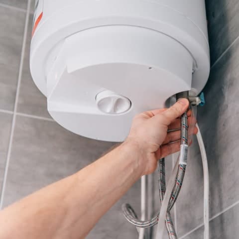 Plumber adjusting the valve on a tank water heater