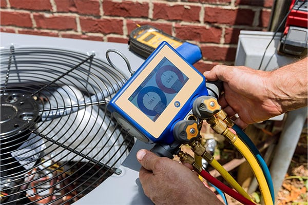 Technician checking refrigerant pressure during an air conditioner repair