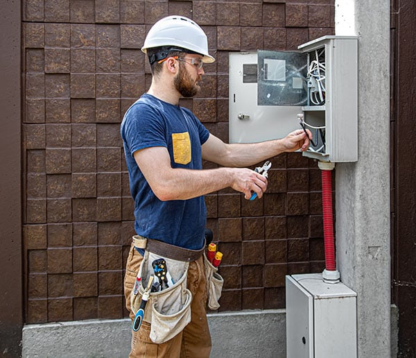 Licensed electrician examining wiring connections inside an electrical panel in Colorado Springs