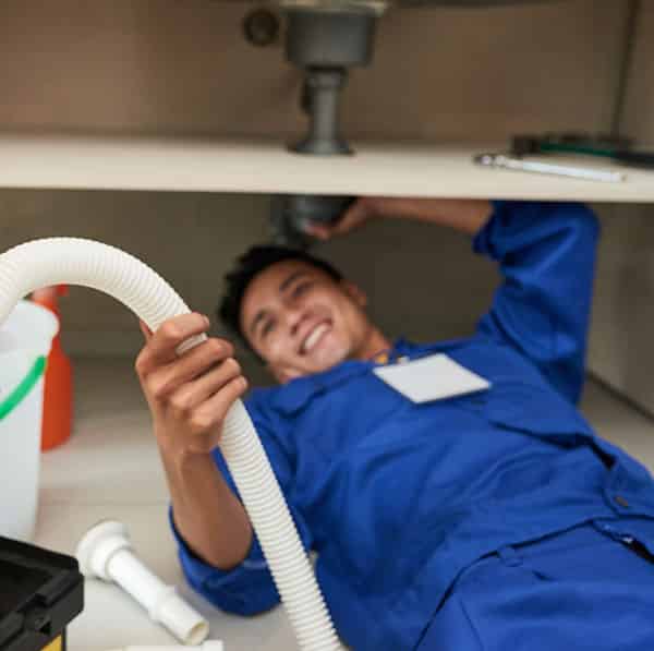 Licensed plumber repairing pipes under a sink